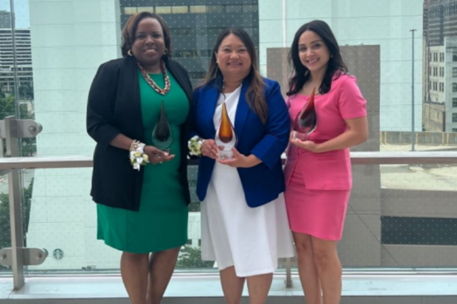 Maysee Yang Herr stands with two other people holding awards.