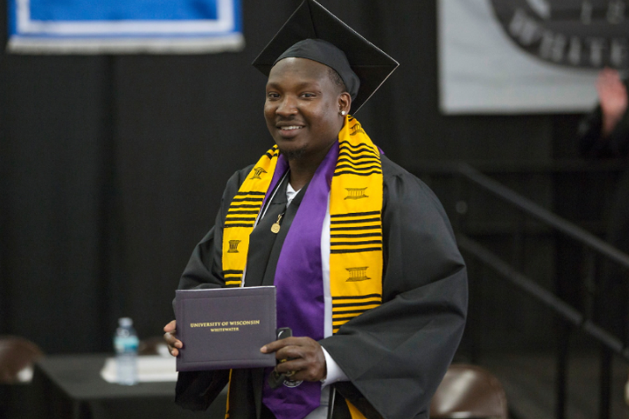 Kyree Brooks dressed in academic regalia holding a diploma.